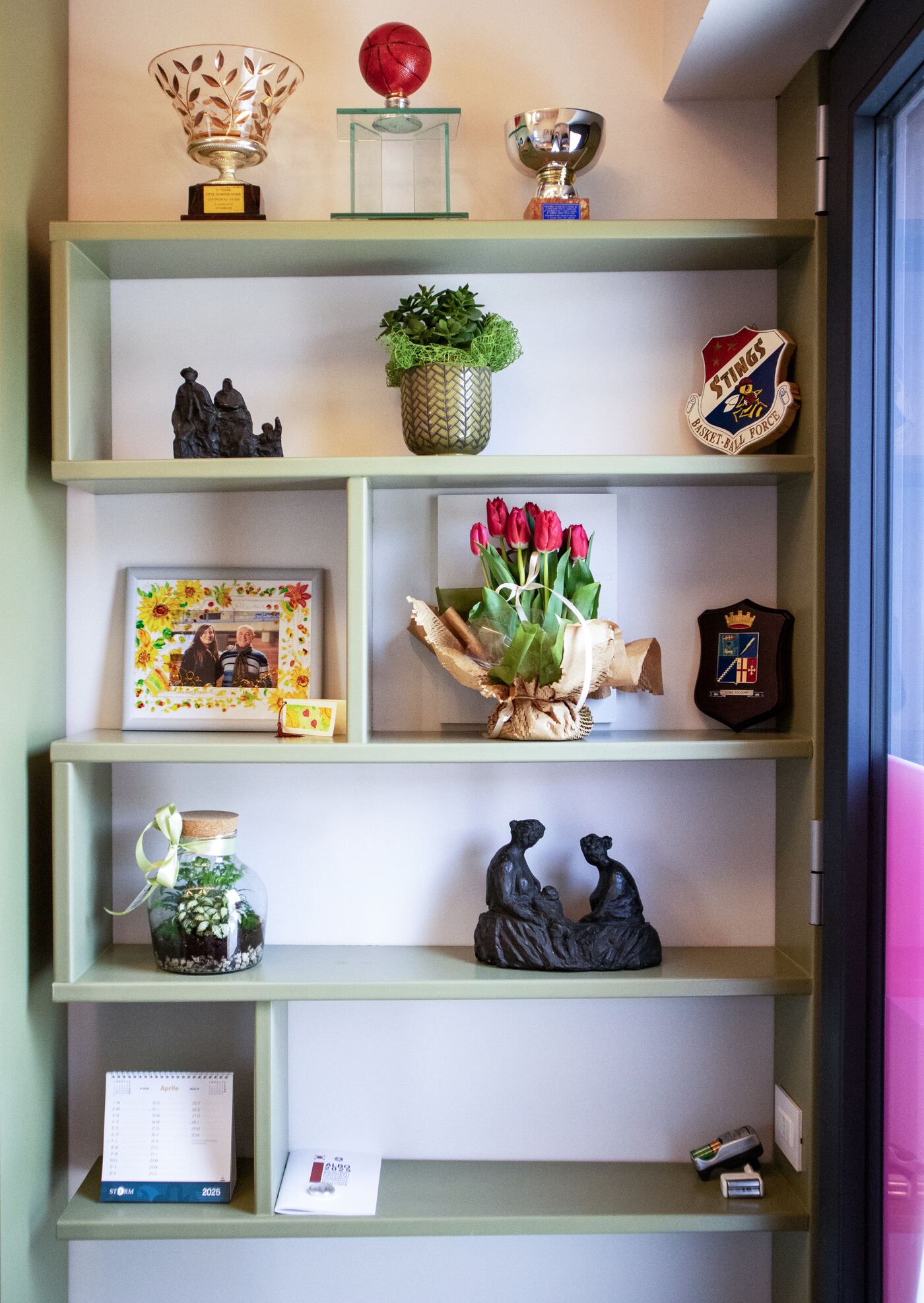 La libreria dell'ufficio con trofei, fiori e oggetti dello studio