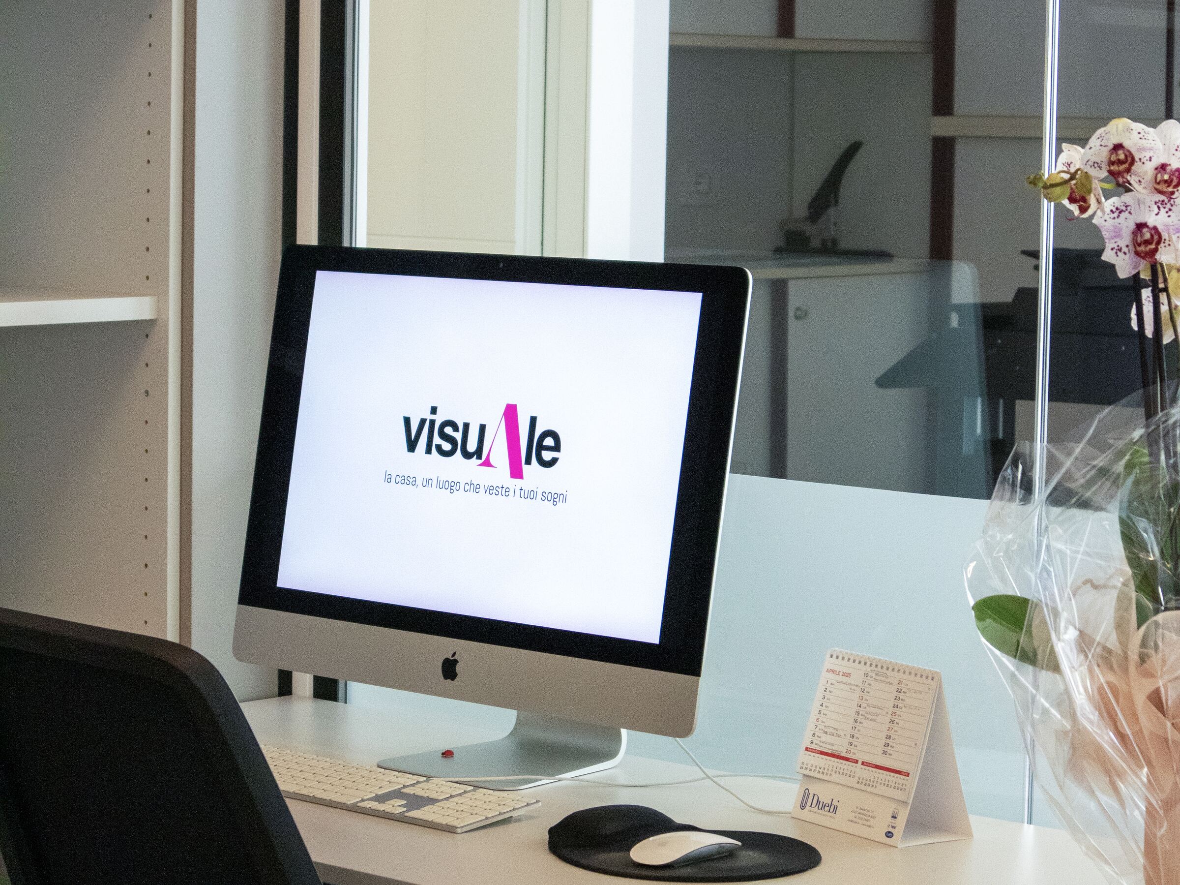 Postazione di lavoro nella sede di visuAle Studio Tecnico, con il logo sullo schermo